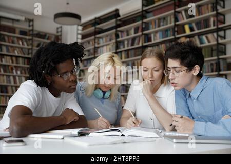 Giovani studenti multietnici concentrati che si preparano agli esami. Foto Stock