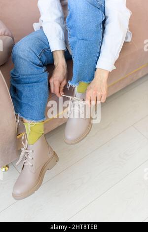 gambe femminili in jeance blu, calze verdi e stivali con lacci in pelle beige. Foto per interni Foto Stock