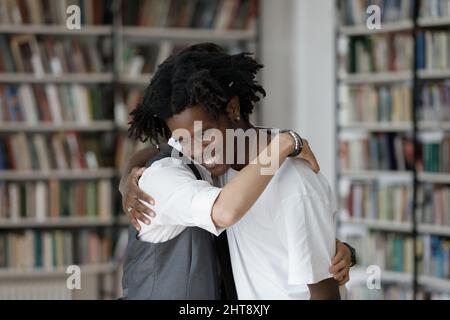 Felice ragazzo giovane coccolare sorridente amico afroamericano. Foto Stock