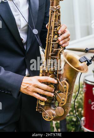 Primo piano di un maschio in un abito elegante che suona il sassofono Foto Stock