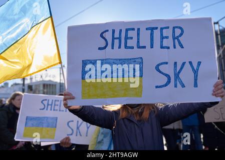 Helsinki, Finlandia - 26 febbraio 2022: Dimostratore in un raduno contro l’occupazione militare russa in Ucraina con il cartello Shelter Sky. Foto Stock