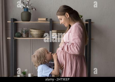 Ragazzo con stetoscopio medico, ascoltando la mamma incinta grande pancia Foto Stock