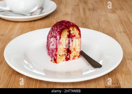 Primo piano di una fetta di torta fatta in casa con velluto rosso e fiocchi di cocco Foto Stock