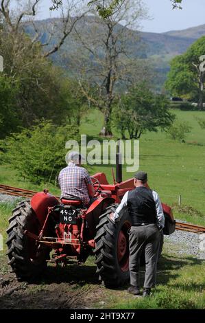 Trattore vintage e re-enattori in attesa di 'Winifred' e treno. Foto Stock