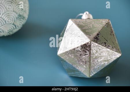 Primo piano di figure geometriche argentate e di icosaedro isolate su sfondo blu Foto Stock