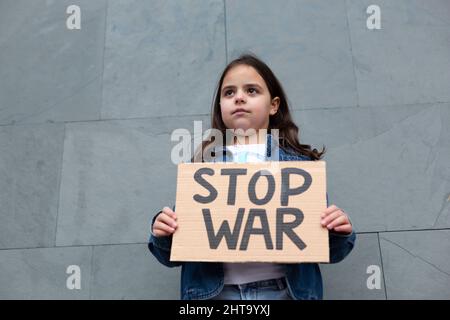 Bambina caucasica che dimostra contro la guerra. Lei è sulla strada tenendo un cartello fatto a mano. Foto Stock