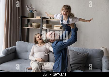 Coppia entusiasta che si aspetta godendo la paternità, giocando con il bambino della figlia anziana Foto Stock