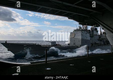 MAR DELLE FILIPPINE (Feb 26, 2022) l'incrociatore missilistico guidato di classe Ticonderoga USS Mobile Bay (CG 53) conduce un rifornimento in mare con la portaerei di classe Nimitz USS Abraham Lincoln (CVN 72). Abraham Lincoln Strike Group è in fase di implementazione pianificata nell'area delle operazioni della flotta USA 7th per migliorare l'interoperabilità attraverso alleanze e partnership, fungendo da forza di risposta pronta a supportare una regione indopacifica libera e aperta. (STATI UNITI Foto Navy di Sint. Di comunicazione di massa Seaman Aprentice Julia Brockman) Foto Stock