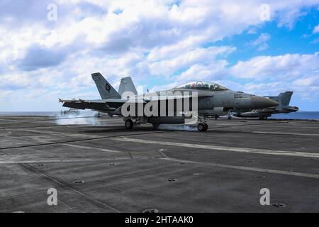 MAR DELLE FILIPPINE (Feb 26, 2022) un F/A-18F Super Hornet, assegnato al "Black Aces" di Strike Fighter Squadron (VFA) 41, sul ponte di volo della portaerei di classe Nimitz USS Abraham Lincoln (CVN 72). Abraham Lincoln Strike Group è in fase di implementazione pianificata nell'area delle operazioni della flotta USA 7th per migliorare l'interoperabilità attraverso alleanze e partnership, fungendo da forza di risposta pronta a supportare una regione indopacifica libera e aperta. (STATI UNITI Foto Navy di Mass Communication Specialist 3rd Classe Javier Reyes) Foto Stock