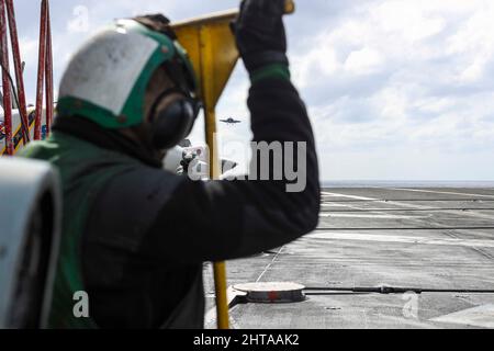 MAR DELLE FILIPPINE (Feb 26, 2022) Airman Richard Boseke, di Hillsboro, Ore., osserva le operazioni di volo sul ponte di volo della portaerei di classe Nimitz USS Abraham Lincoln (CVN 72). Abraham Lincoln Strike Group è in fase di implementazione pianificata nell'area delle operazioni della flotta USA 7th per migliorare l'interoperabilità attraverso alleanze e partnership, fungendo da forza di risposta pronta a supportare una regione indopacifica libera e aperta. (STATI UNITI Foto Navy di Mass Communication Specialist 3rd Classe Javier Reyes) Foto Stock