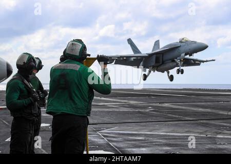 MAR DELLE FILIPPINE (Feb 26, 2022) i marinai osservano le operazioni di volo sul ponte di volo della portaerei di classe Nimitz USS Abraham Lincoln (CVN 72). Abraham Lincoln Strike Group è in fase di implementazione pianificata nell'area delle operazioni della flotta USA 7th per migliorare l'interoperabilità attraverso alleanze e partnership, fungendo da forza di risposta pronta a supportare una regione indopacifica libera e aperta. (STATI UNITI Foto Navy di Mass Communication Specialist 3rd Classe Javier Reyes) Foto Stock