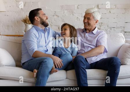 Gli uomini felici multi generazionali siedono sul divano nel soggiorno Foto Stock