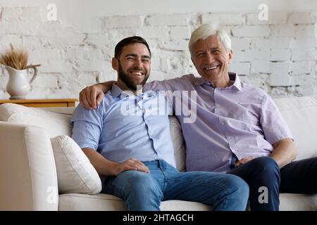 Sorridendo l'uomo più vecchio suo figlio grovigliato che abbraccia guardare la macchina fotografica Foto Stock