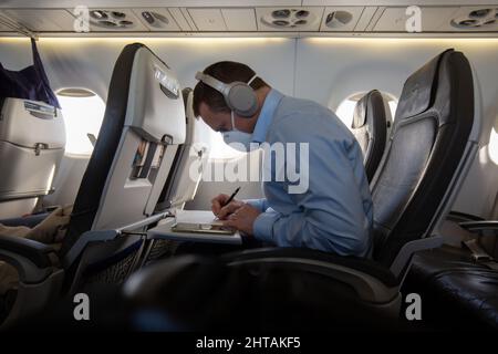 Persona che indossa una maschera facciale e lavora sull'aereo Foto Stock