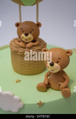 Foto di orsacchiotto in un topper palloncino e un topper di orsacchiotto seduto su una torta verde Foto Stock