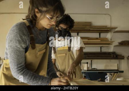 Giovane coppia di carpentieri che lavorano in una piccola officina di carpenteria - giovani imprenditori a Lisbona Foto Stock