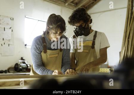 Giovane coppia di carpentieri che lavorano in una piccola officina di carpenteria - giovani imprenditori a Lisbona Foto Stock