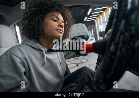 Le donne lavoratrici concentrate puliscono le superfici interne dell'auto Foto Stock