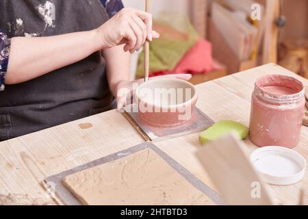 Pittura femminile a mano con una spazzola ceramica di colore rosa Foto Stock