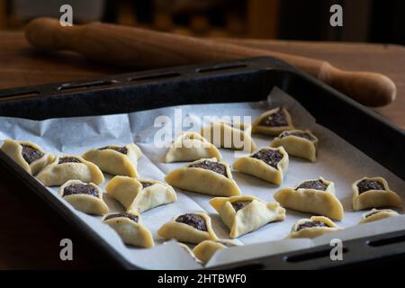 Molte "tasche di Haman" precotte, note anche come Hamantashen, un Ashkenazi Jewish triangolare riempito-tasca biscotti, di solito associati con il hol ebraico Foto Stock