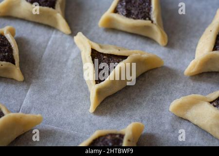 Le "tasche di Haman" precotte, note anche come Hamantashen, un Ashkenazi Jewish triangolare riempito-tasca biscotti, di solito associati con la festa ebraica Foto Stock