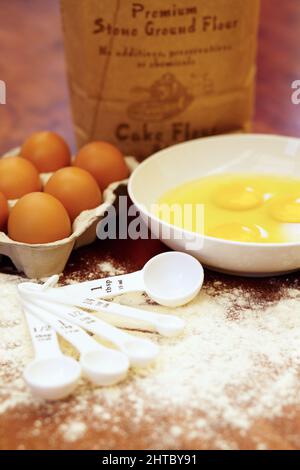 È il momento di cuocere qualcosa di gustoso. Shot di una varietà di ingredienti e strumenti di misurazione su un tavolo di legno. Foto Stock