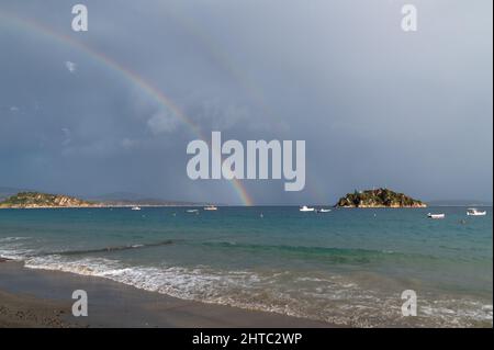 Arcobaleno e barche da pesca in mare. La foto è stata scattata in una giornata nuvolosa Foto Stock