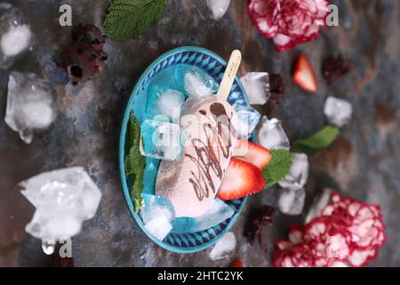 Primo piano di un pop-up fatto in casa con sapori diversi su tavola nera con frutta su un piatto blu Foto Stock