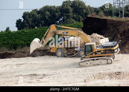 Attrezzature per movimento terra pesante che liberano il terreno per un progetto di ingegneria civile su larga scala Foto Stock