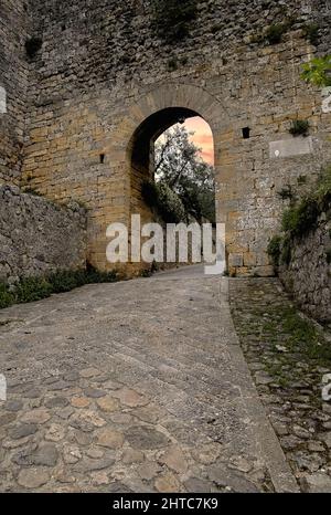 L'antica via Francigena di pellegrinaggio dalla Cattedrale di Canterbury in Inghilterra a Roma, passando per la Francia e la Svizzera, passava attraverso la porta Fiorentina o porta San Giovanni, la porta settentrionale, rivolta verso Firenze, nelle mura medievali che circondano la città di Monteriggioni, in cima alla collina, in Toscana, Italia. Foto Stock