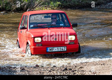 Madona, Lettonia - 01 maggio 2021: La Fiat 126, una vettura rossa a tempo indolo, supera l'ostacolo all'acqua Foto Stock