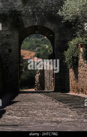 L'antica via Francigena di pellegrinaggio dalla Cattedrale di Canterbury in Inghilterra a Roma, passando per la Francia e la Svizzera, passava attraverso la porta Fiorentina o porta San Giovanni, la porta settentrionale, rivolta verso Firenze, nelle mura medievali che circondano la città di Monteriggioni, in cima alla collina, in Toscana, Italia. Foto Stock