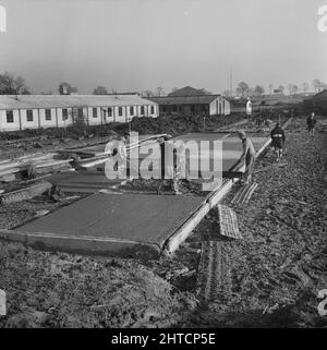 RAF Gaydon, Gaydon, Stratford-on-Avon, Warwickshire, 21/01/1953. Uomini che effettuano lavori di costruzione a Gaydon Airfield, versando e livellando calcestruzzo durante la cementazione dell'impronta di un edificio. I lavori iniziarono alla costruzione di una nuova pista a Gaydon Airfield all'inizio del 1952. A ciò seguì un secondo contratto per la costruzione di oltre 100 edifici Easiform e Air Ministry. Questi includevano una torre di controllo del traffico aereo, cinque caldaie, capanne di airmen, messes, e un NAAFI. Il più grande edificio Easiform del sito era un centro di formazione, che aveva una superficie di quasi 3.000 piani Foto Stock