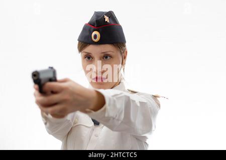 Una bella giovane donna polizia russa poliziotto tenente colonnello in abito uniforme in un cappello con una pistola nelle sue mani su uno sfondo bianco. Selectiv Foto Stock