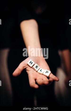 Ragazza che chiede aiuto. Ragazza allunga le mani con la parola aiuto nelle sue palme Foto Stock