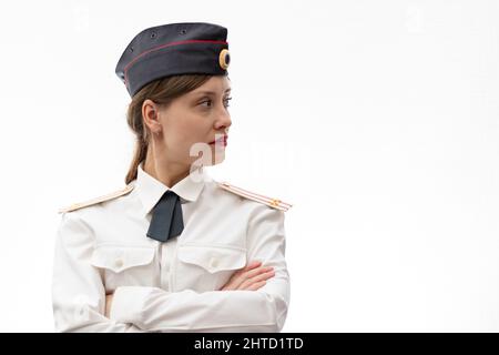 Una bella giovane donna russa ufficiale di polizia in uniforme vestito in una berretto e spalline di un tenente colonnello e una camicia bianca su un bianco bac Foto Stock