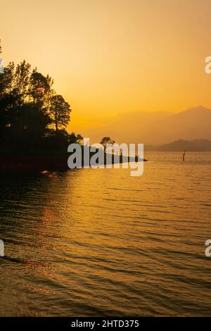 Vista mozzafiato del lago al tramonto con magnifici alberi sullo sfondo. Bel click da Banasura Sagar Dam Wayanad Foto Stock
