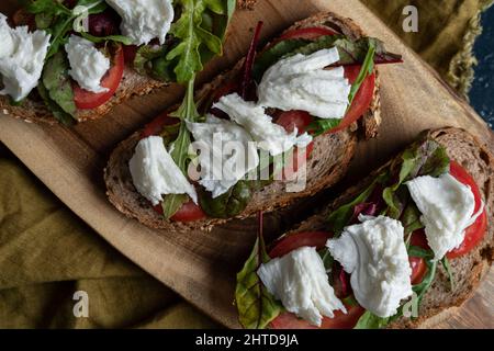 Un'immagine a testa di sandwich di pane di campagna appena sfornato con mozzarella, pomodori e rucola Foto Stock