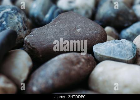 Primo piano di grande grunge pietra su un piccolo ciottoli pietre Foto Stock