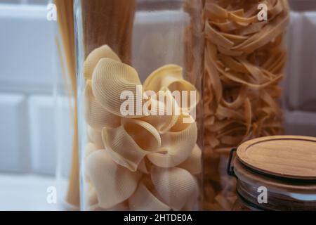 Varietà di pasta in vasetti di vetro con pasta rigata in primo piano Foto Stock