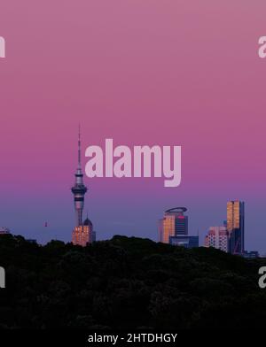 Vista di una torre del cielo durante il tramonto con il riflesso del sole di colore viola e blu nel cielo Foto Stock