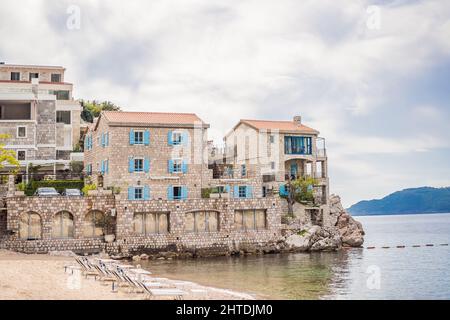 Pittoresca vista estiva della costa adriatica della Riviera di Budva vicino al villaggio di Przno. Spiaggia accogliente ed edifici sulla roccia. Ubicazione: Villaggio di Przno Foto Stock