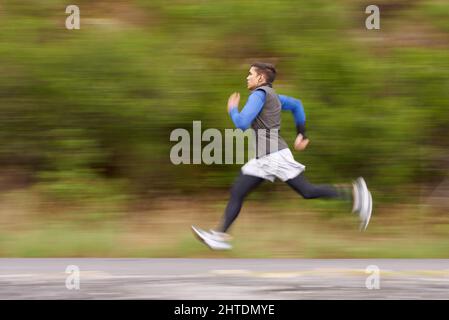 Bruciando via le miglia. Il movimento offuscava l'immagine di un giovane che corre lungo la strada. Foto Stock