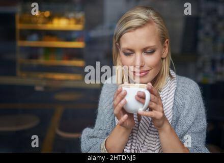 Abbiamo tutti bisogno di un posto per essere soli. Una giovane donna seduta in una caffetteria. Foto Stock