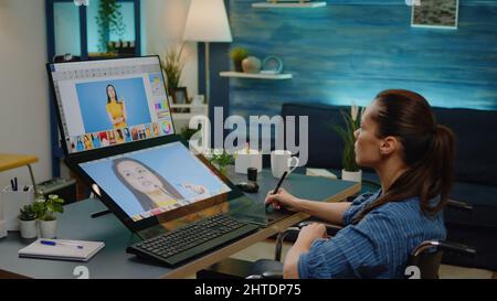 Disattivato l'editor tenendo premuto lo stilo mentre si esegue il ritocco delle immagini in media studio a casa. Fotografo seduto su sedia a rotelle e utilizzando l'applicazione di modifica sul touch screen per la produzione di immagini Foto Stock