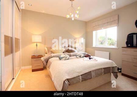 Camera da letto moderna ragazzi in casa nuova costruzione, tema rugby, copriletto, schema colore beige neutro, alto imbottito testiera, palle di rugby, camera da letto ragazzi, Foto Stock