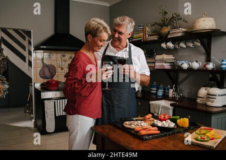 Coppia anziana caucasica che abbraccia mentre cucinano in cucina Foto Stock