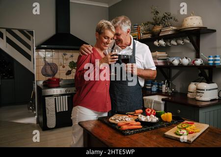 Coppia caucasica maggiore bere vino in cucina cena Foto Stock