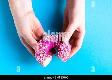 Mano che tiene metà mangiato dolce rosa ciambella isolato. Metà mangiato ciambella isolato. Foto Stock