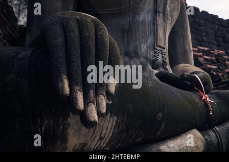 Primo piano di una mano di una scultura di Buddha in un antico tempio in Thailandia Foto Stock